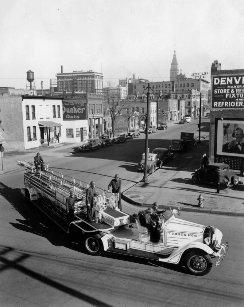 Archival photo of street scene with fire truck in the foreground.