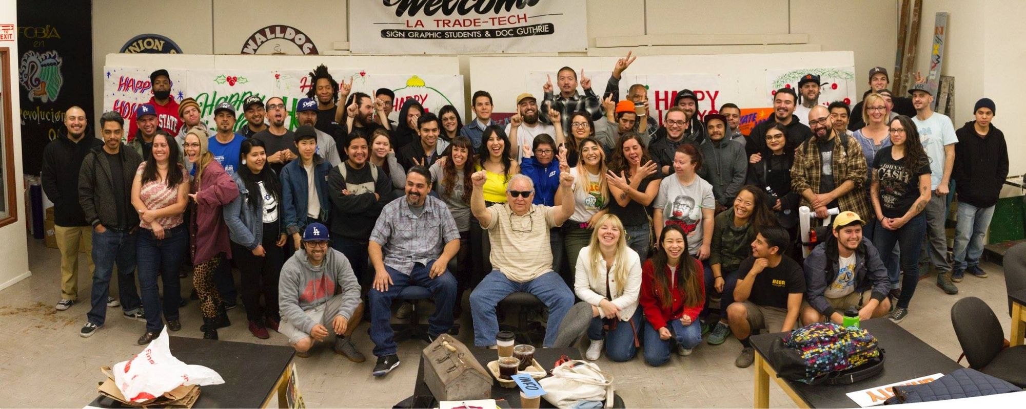 Group photo with various hand-painted signs laid out on a pair of wide easels as a backdrop.