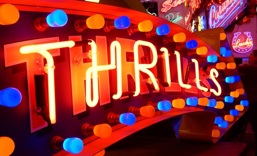 Neon sign set in an arrow with coloured light bulbs surrounding the lettering.