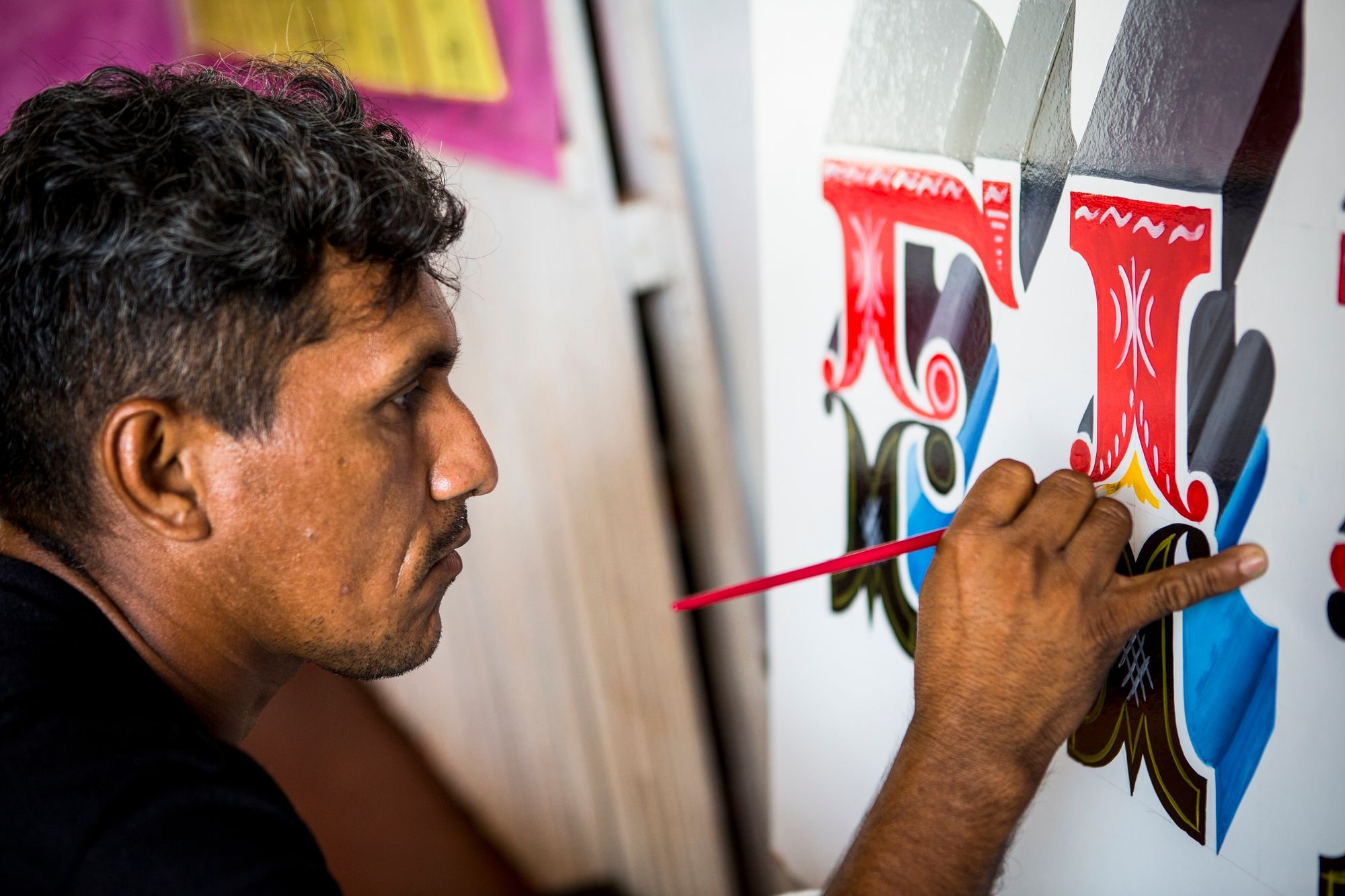 Man painting Tuscan lettering on a boat.