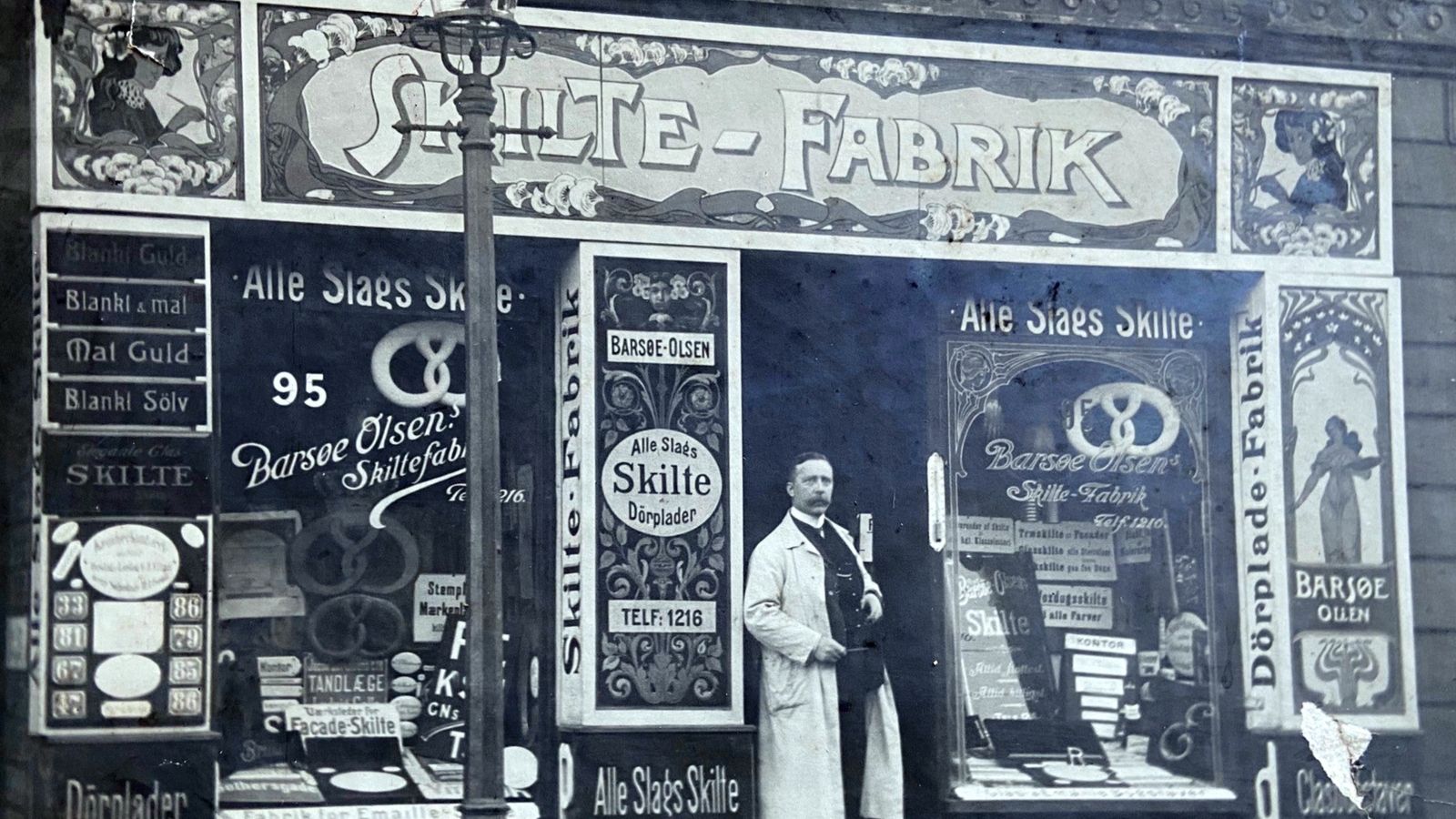 Man standing outside a shop adorned with numerous signs.