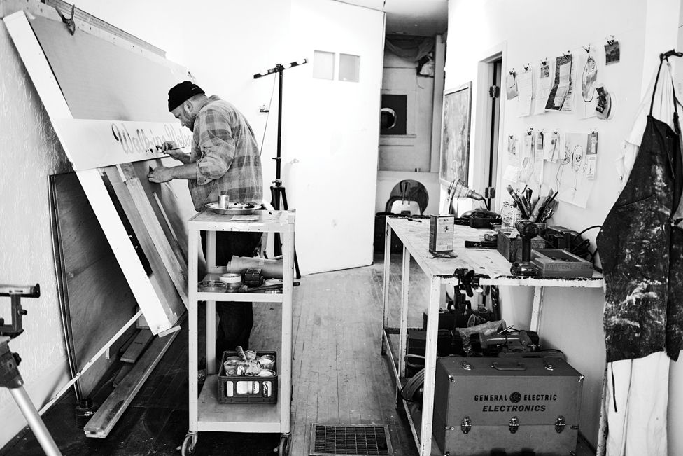 Man at an easel in a sign painting studio.
