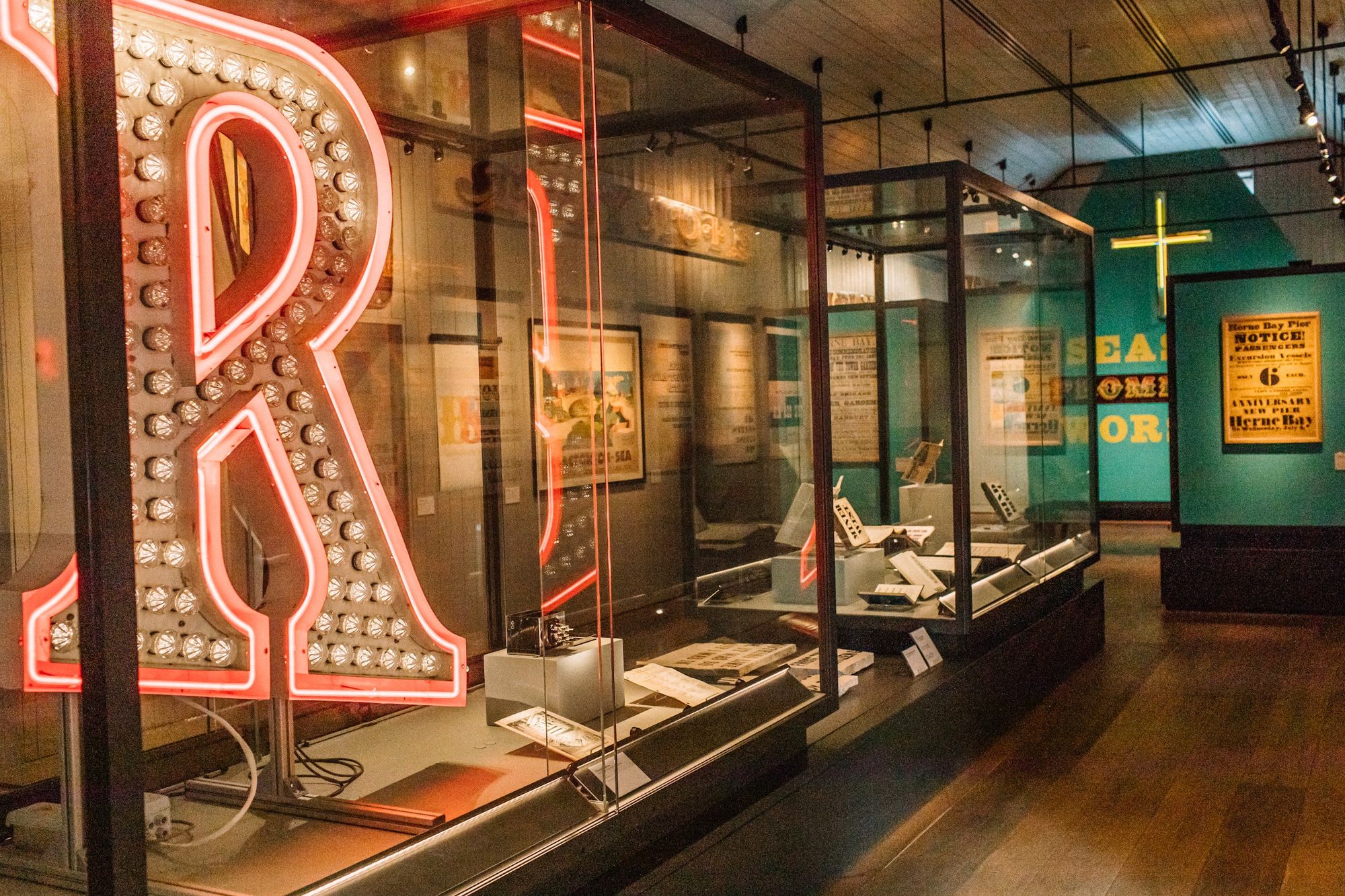 An exhibition space with a capital R illuminated by white bulbs on the inside and a red neon outline. 