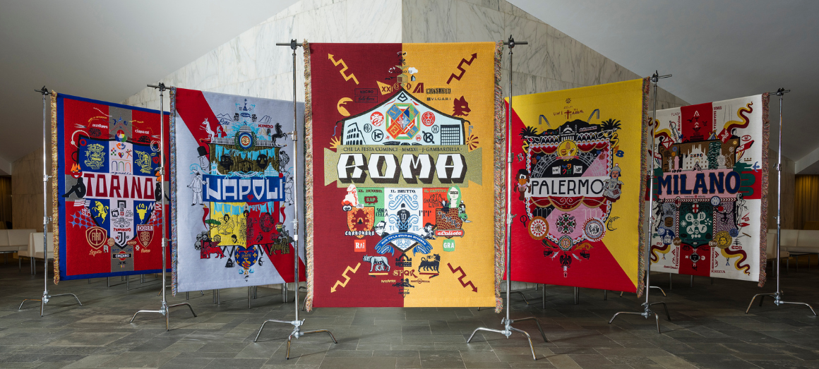 Embroidered banners on display in a gallery setting.