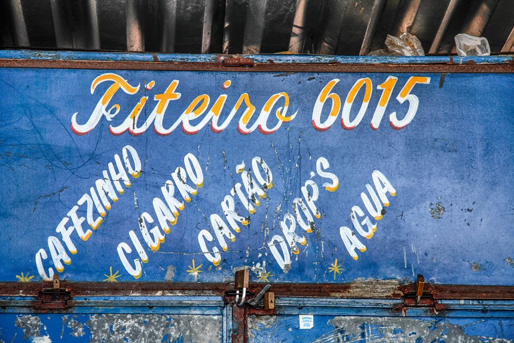 Hand-painted lettering in white, yellow, and red on a blue metal structure.