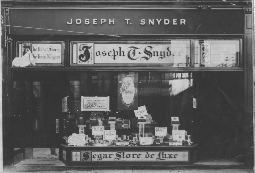 Shopfront with entrances left and right flanking a central window which has a display.