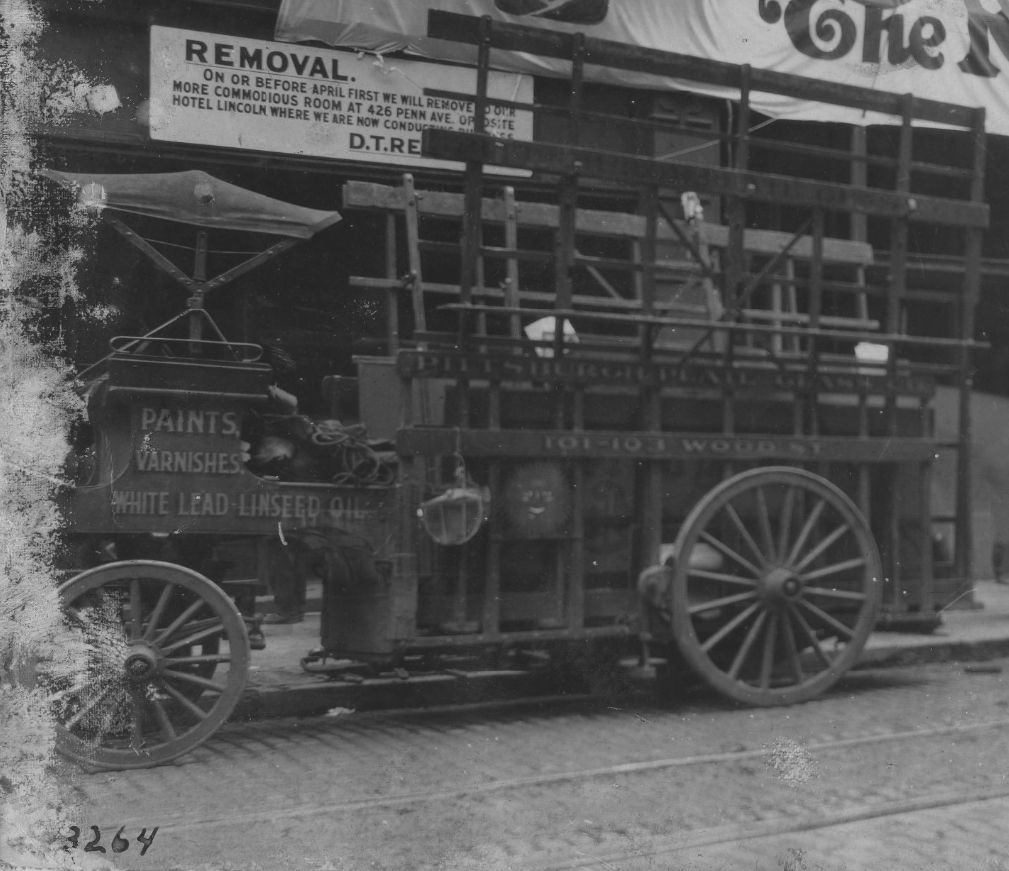 Wagon with wooden wheels and space for storing large glass panels on the rear.