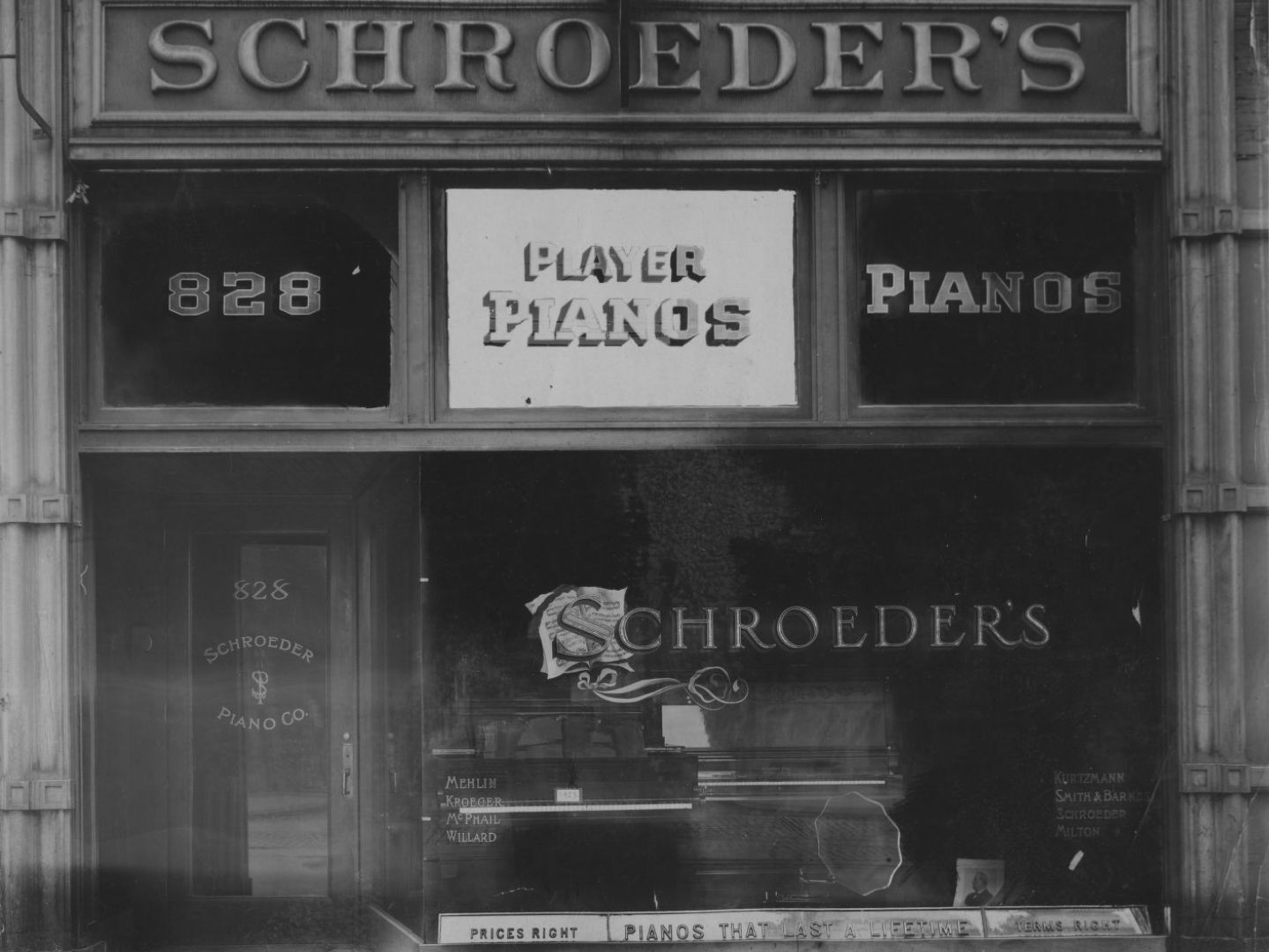 Shop front with a fascia sign, and hand-painted and gilded pieces of signage in the window and transoms.