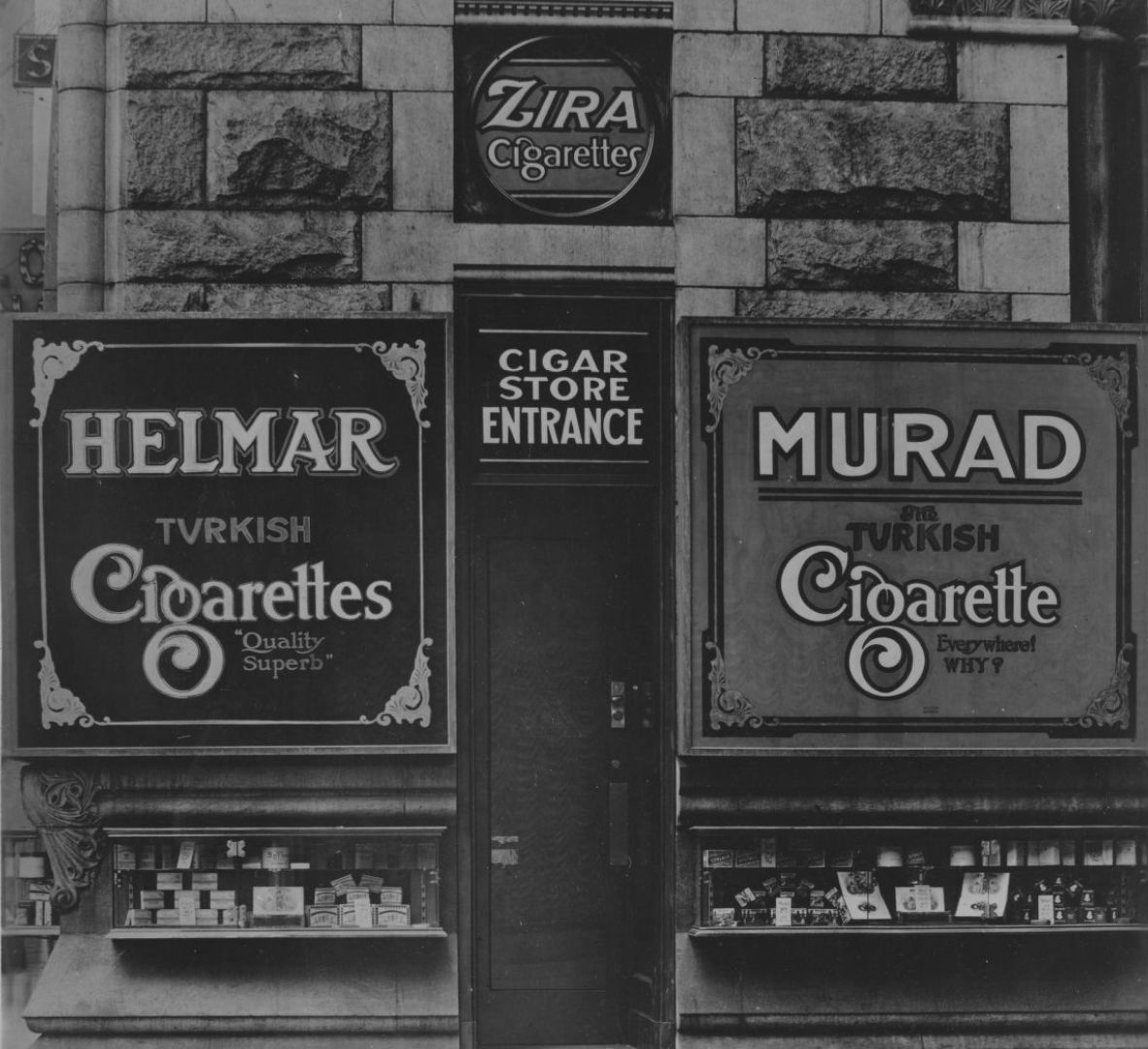 Side door for a shop with small window displays and large cigarette advertisements either side.