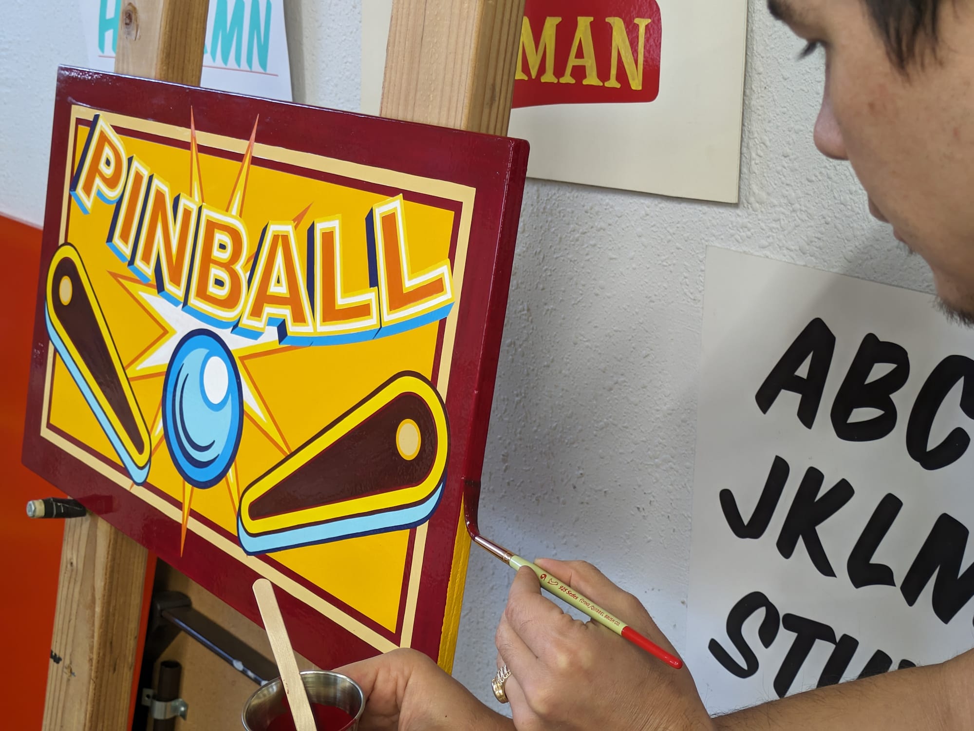 Main painting the edge of a flat panel with the front having the word 'Pinball' and an illustration of the ball and flippers.