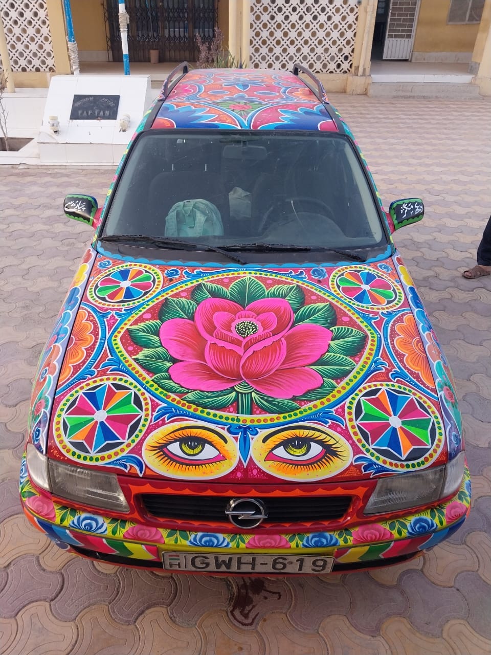 View from the front of a brightly painted Opel car. The decorations cover every available space with pictures, patterns, and motifs.