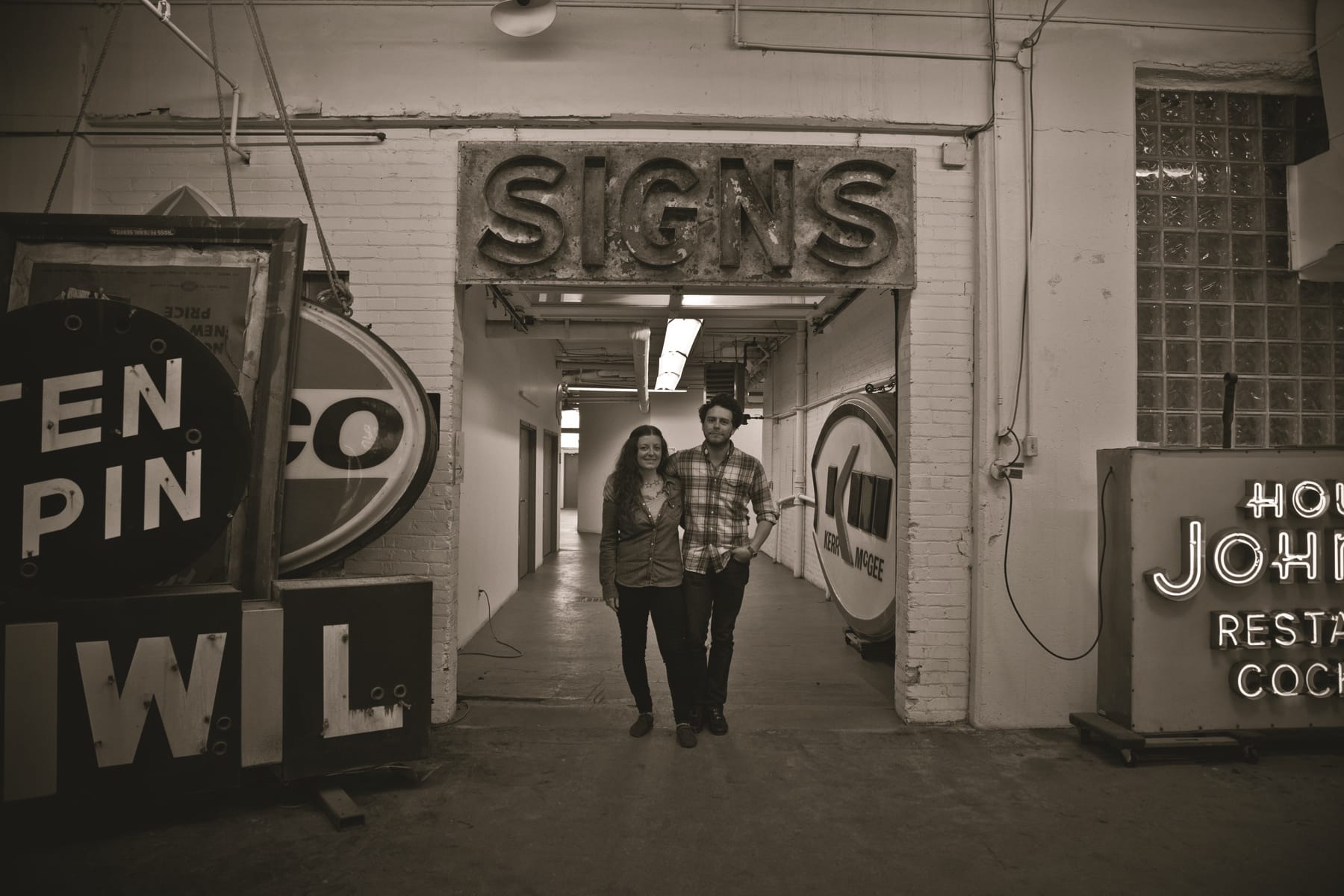 Portrait in a warehouse-style space with various pieces of vintage signage on display.