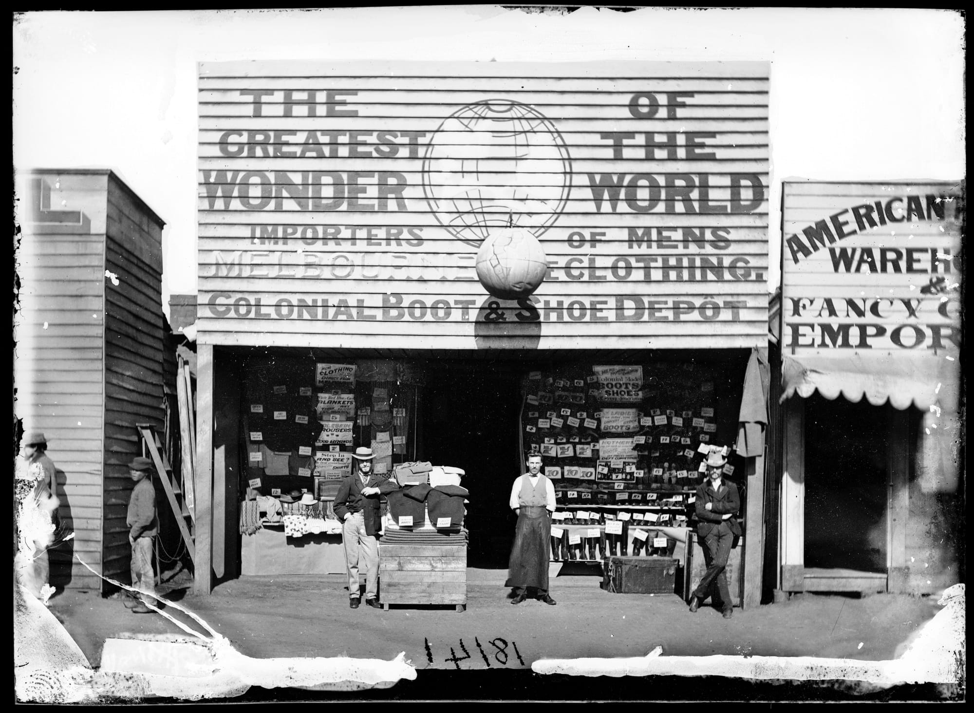People posing for a photo in front of a show and clothing shop with an oversized fascia sign that reads 'the greatest wonder of the world'.