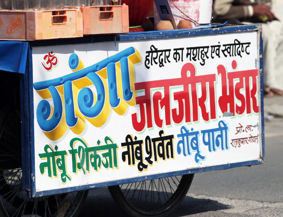 Brightly coloured Hindi scripts on a hand-painted sign mounted to the back of a food truck.