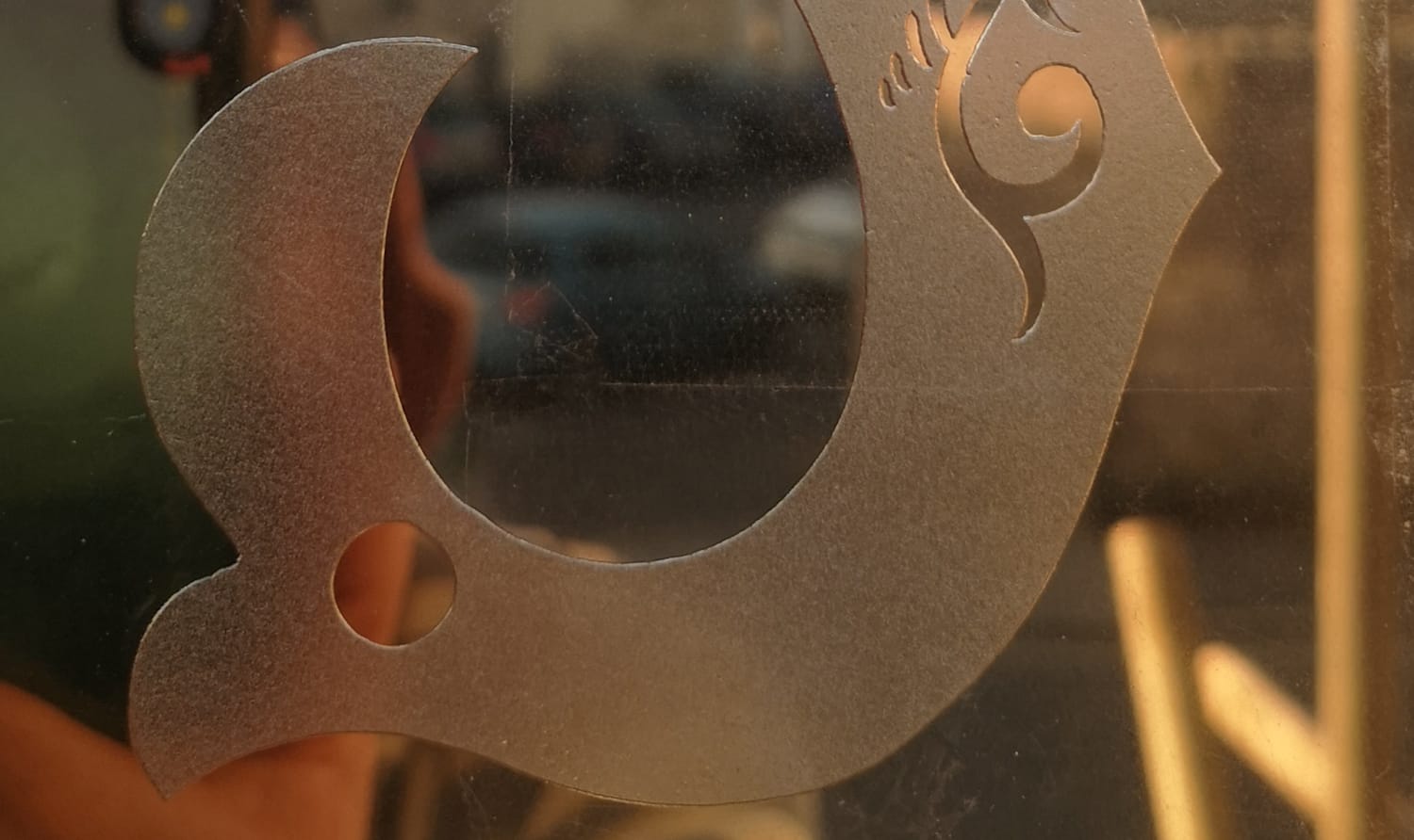 Close up of the lower part of the letter S which has been etched into the glass and appears slightly frosted/dappled versus the clear surrounds.