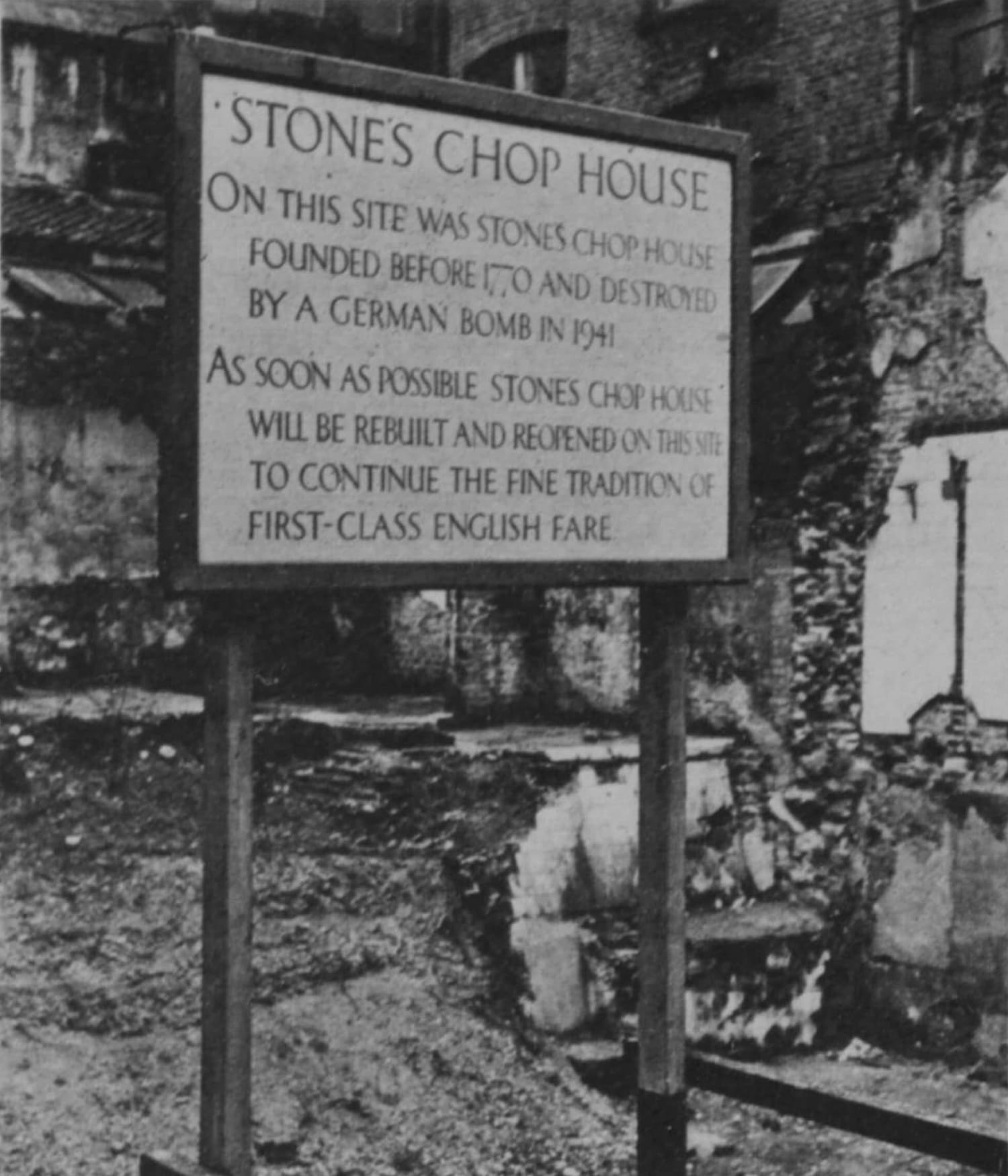Hand-painted sign mounted to two wooden posts. It reads, ""Stones Chop House. On this site was Stones Chop House, founded before 1770 and destroyed by a German bomb in 1941. As soon as posible Stones Chop House will be rebuilt and reopened on this site to continue the fine tradition of first-class English fare."