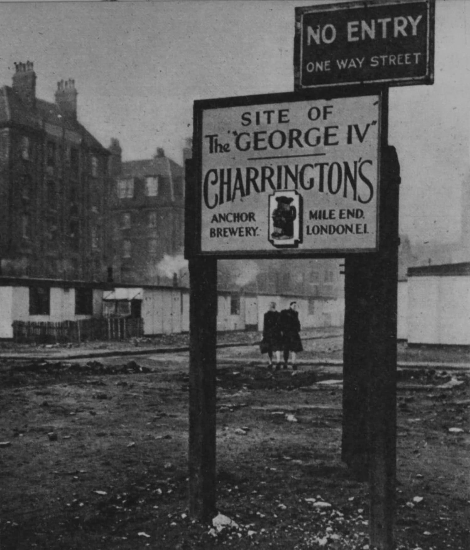 A sign post on flat land with buildings behind it. There are two signs, one above the other. The uppermost reads "No Entry. Once Way Street", while the one below says, "Site of the 'George IV'. Charrington's, Anchor Brewery, Mile End, London E1."