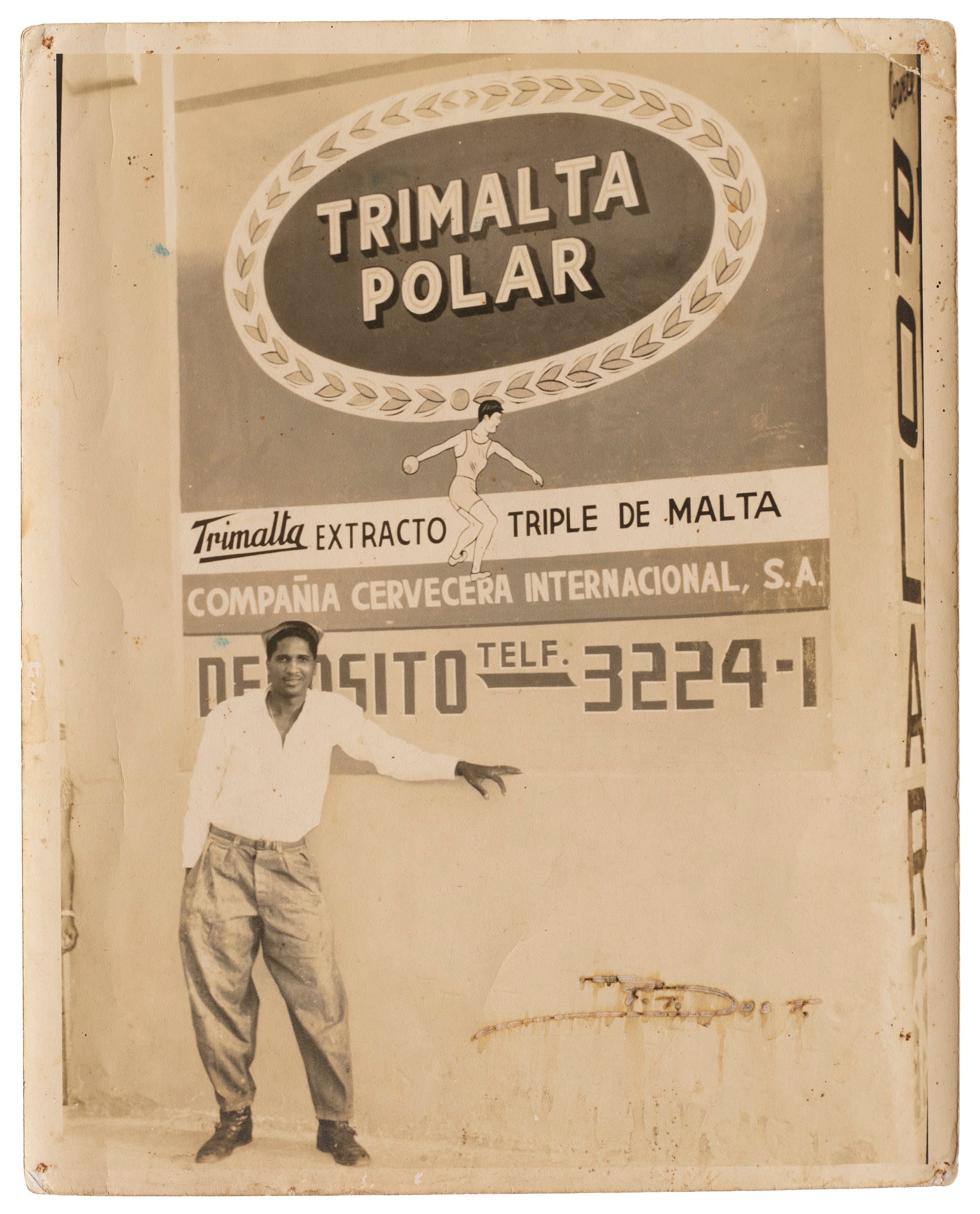 Smartly dressed man posint in front of a painted wall advertisement for 'Trimalta Polar'.