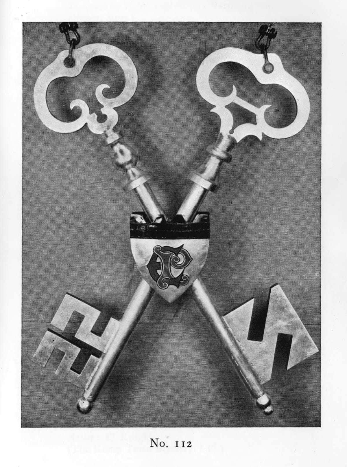 Hanging sign formed of two oversize keys in an X-shape and a small shield mounted where they cross.