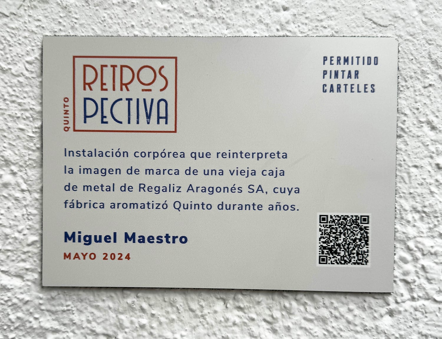 Simple plaque with Quinto Retrospectiva branding, a single sentence/paragraph about the installation, the artist's name and date of production (May 2024) and a QR code.