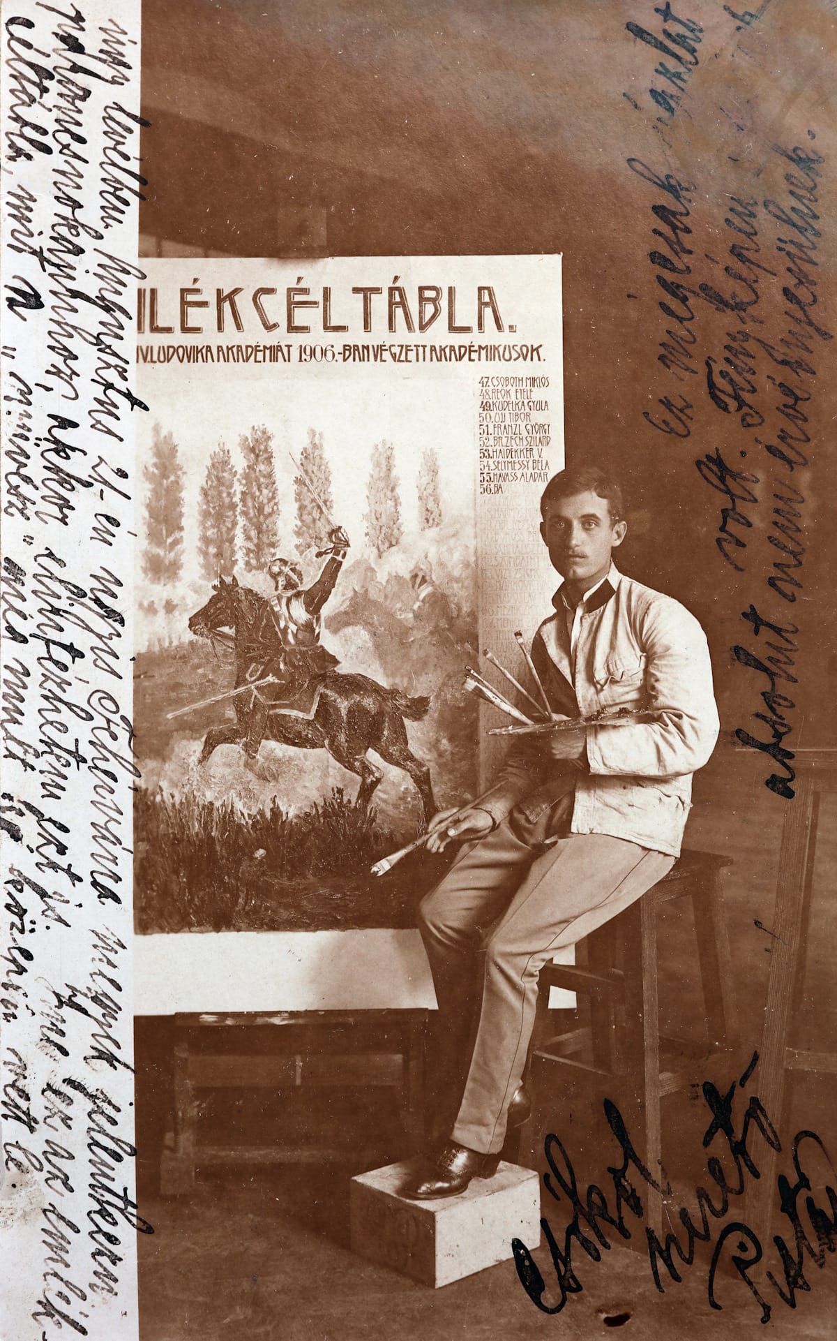 Black and white photo with various bits of handwritten text on and to the side of the picture. The photo is a portrait of a painter siting in front of an easel that he's working on, holding brushes and a pallete. The board he's working on shows a knight on horseback and then there is lettering above this and a list of numbers and names running vertically down the right side.