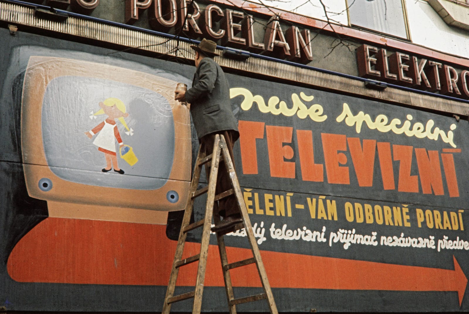 A slightly different angle of the same man at work on the painted billboard advertising televisions.