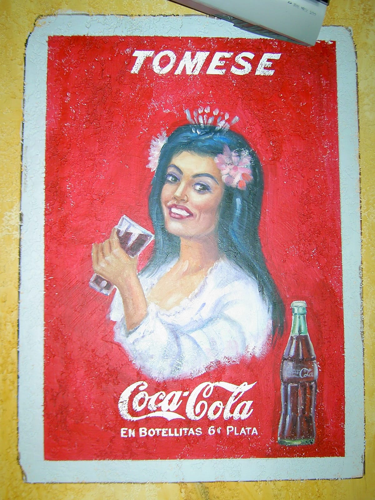 Mural of a Coca-Cola psoter showing a woman drinking a bottle and the headline 'Tomese'