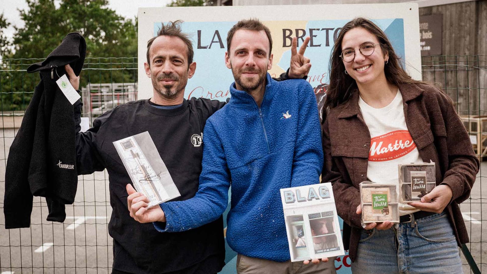 Three people posing for a photo with prizes they've won.