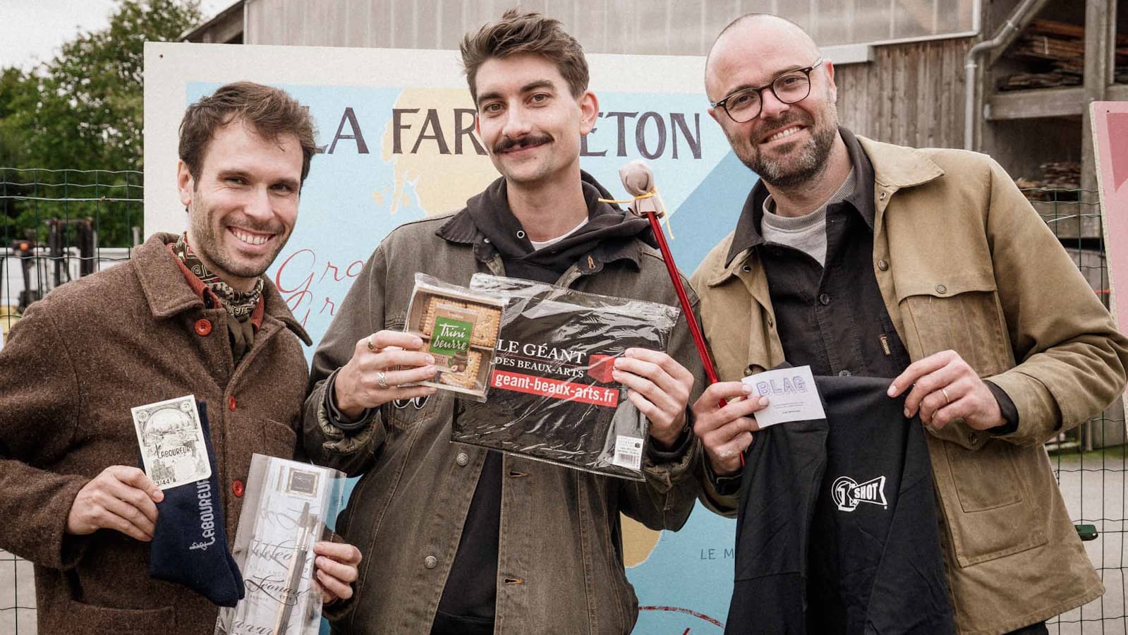 Three people posing for a photo with prizes they've won.