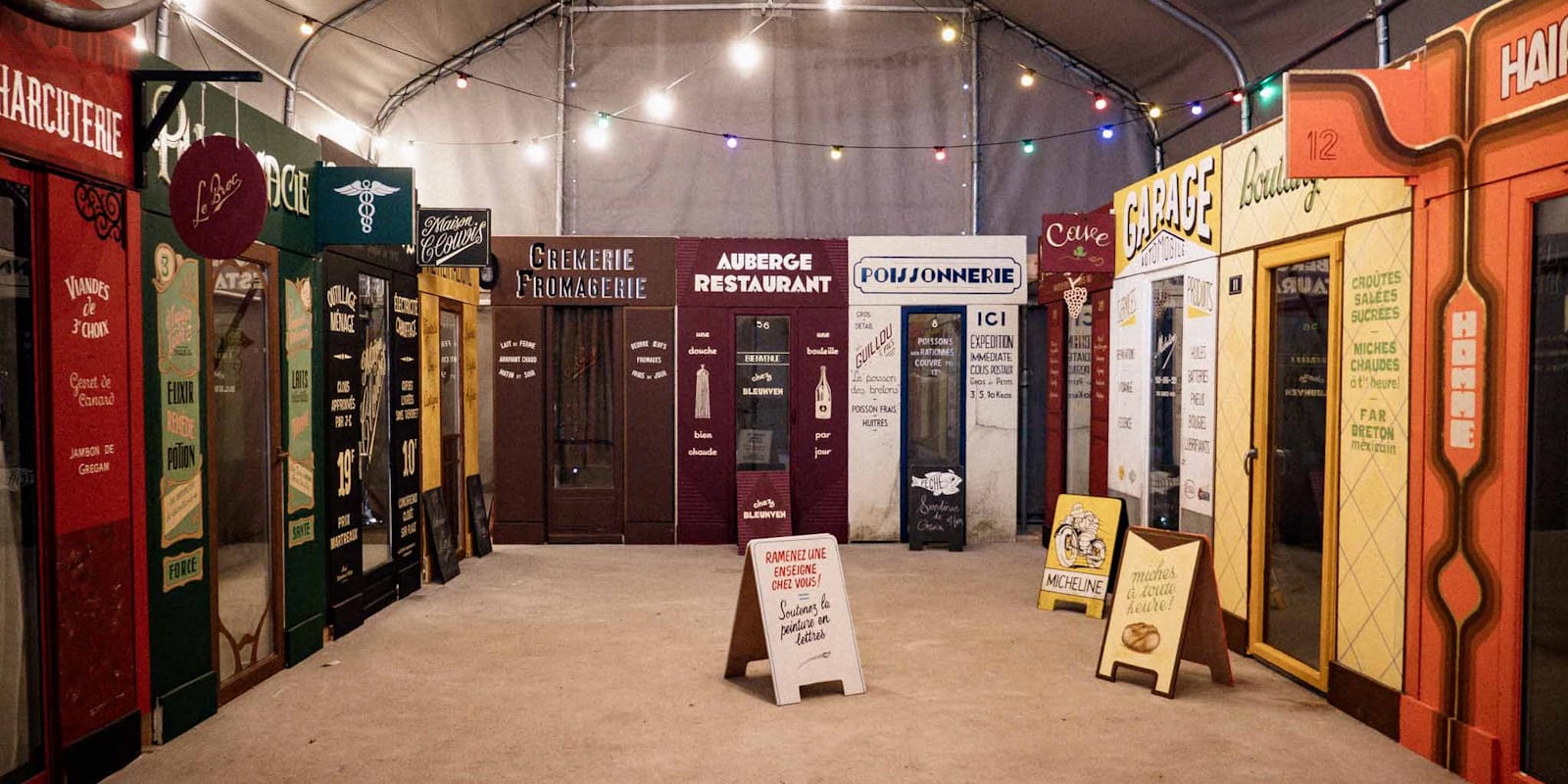 Display of fake shopfronts lettered and decorated in a variety of era-appropriate styles.