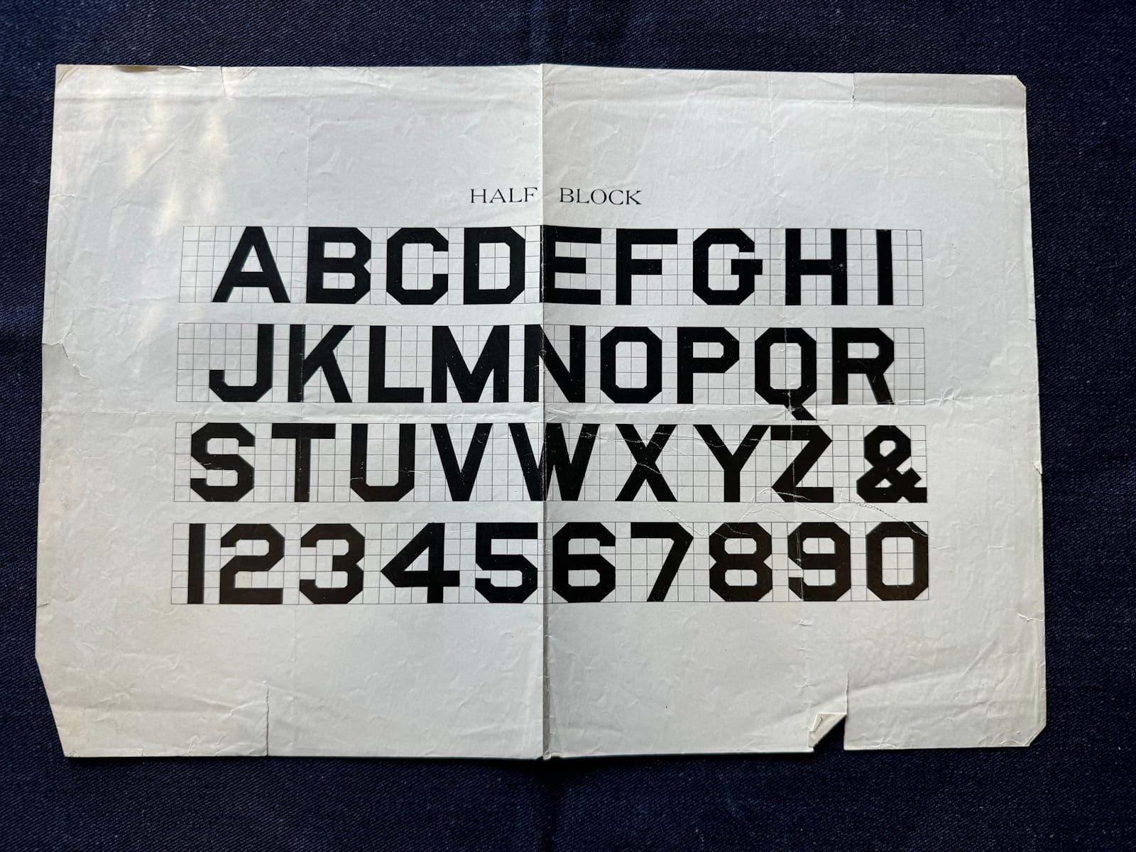 Uppercase block alphabet and numerals with 45 degree corners used on curved characters. The lines are set on a squared grid, with the characters measuring five squares high.