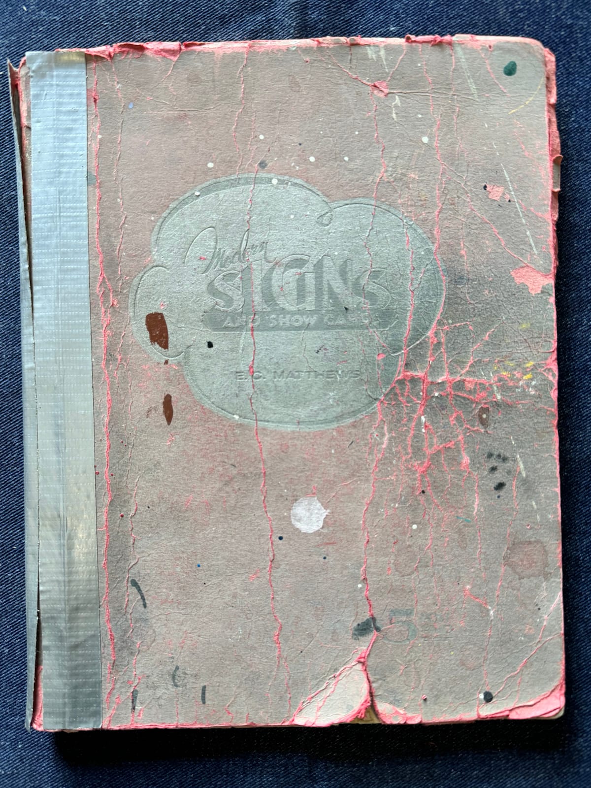 Cover of a book with numerous cracks and other signs of wear.