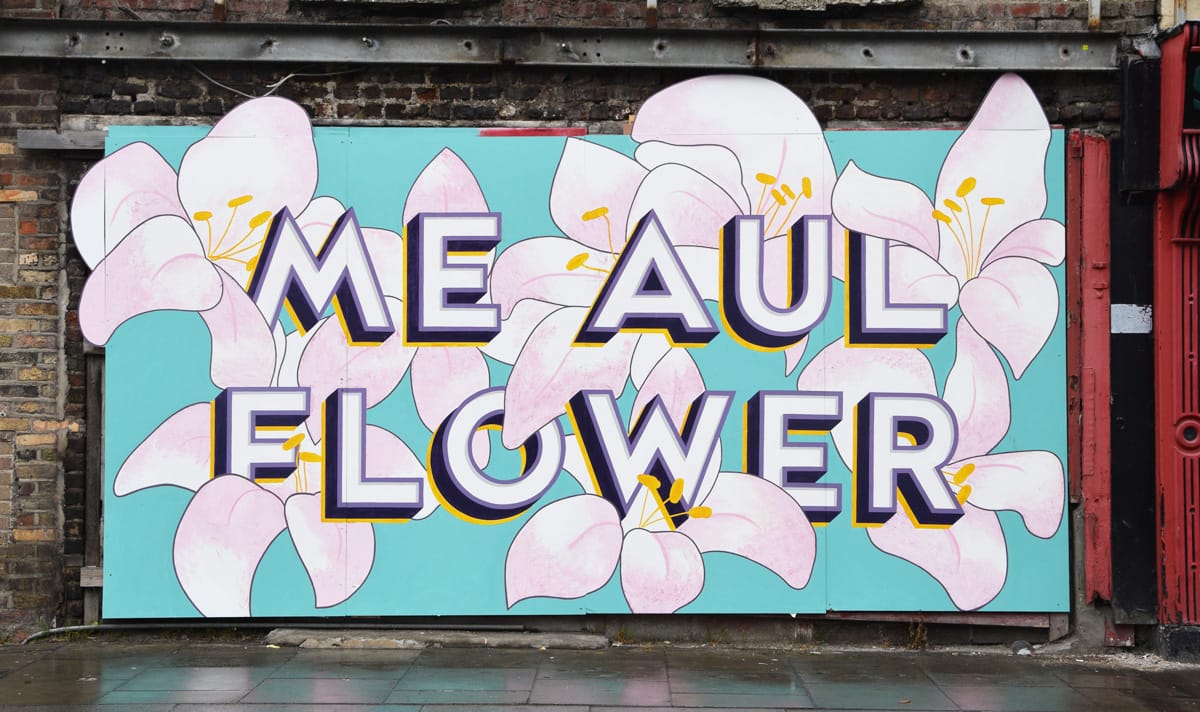 Mural with block and shade lettering for 'Me Aul Flower' set within an array of pale pink flowers. 