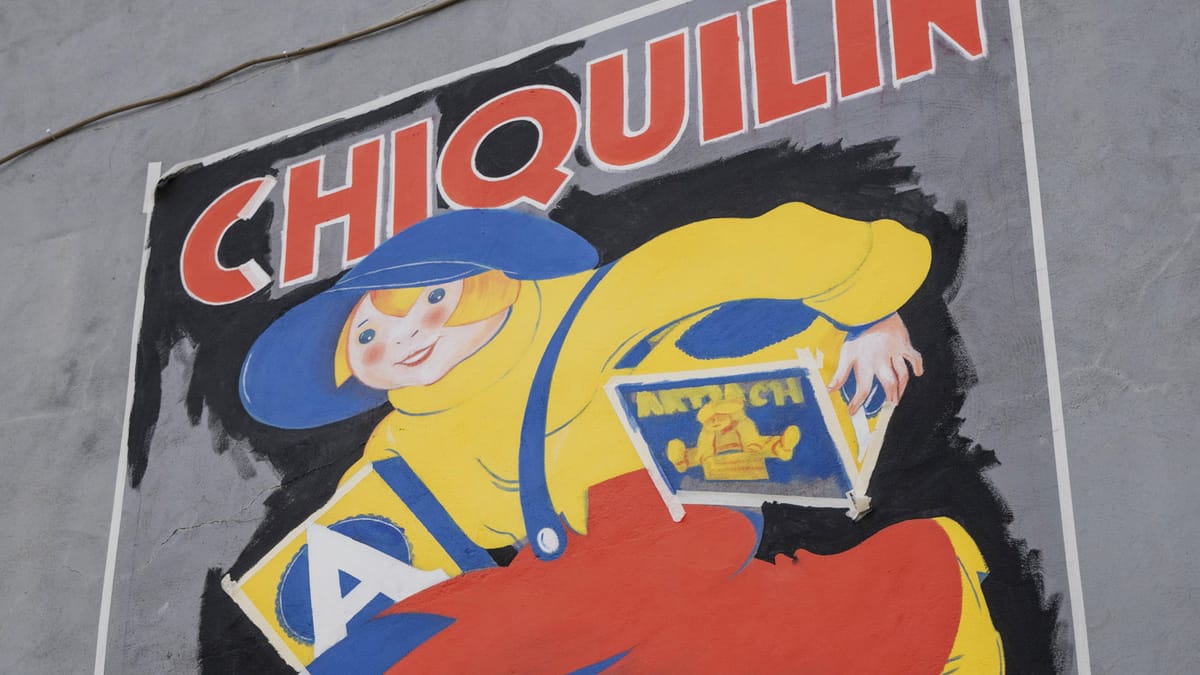 Portion of a painted wall sign showing a boy running with boxes under his arms and lettering that reads "Chiquilin".