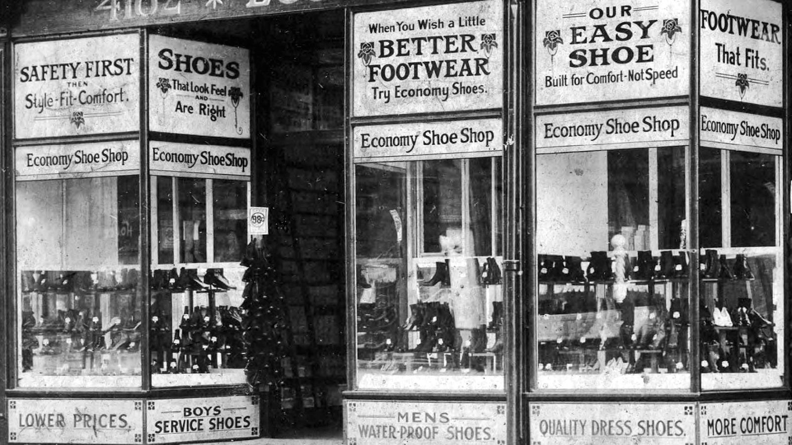 Shoe shop with window displays and numerous pieces of promotional signage above and below these.
