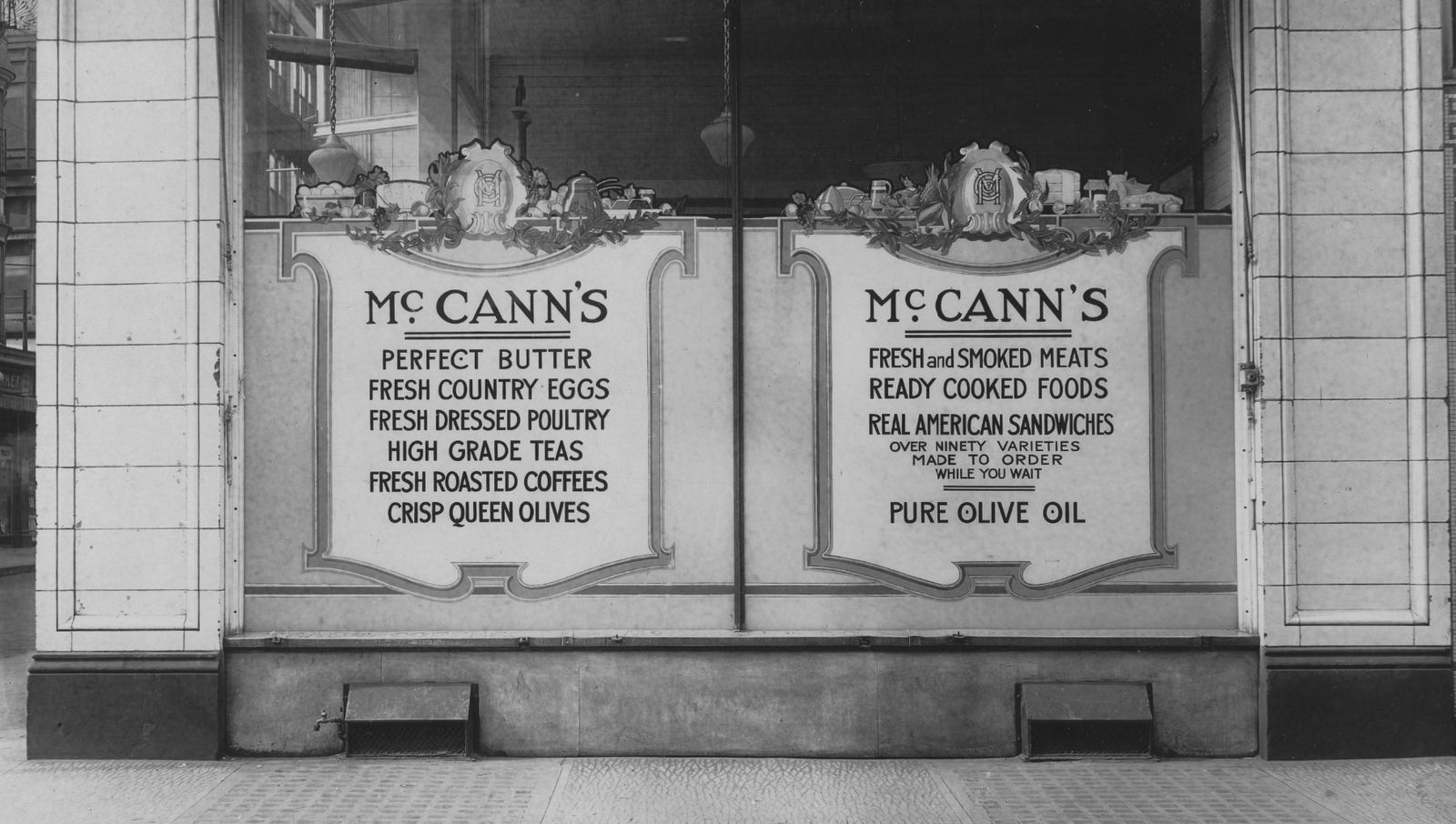 Shop window with two hand-painted decorative panels advertising a variety of food products available within.