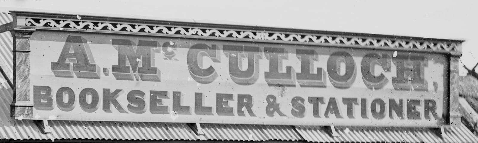 Roof-mounted sign with a mixture of slab-serif and block lettering for 'A. McCulloch, Bookseller & Stationer'.