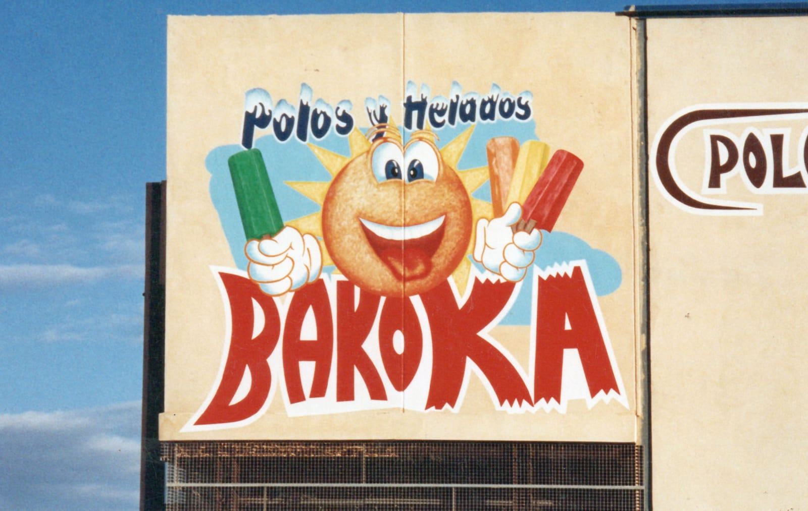 Hand-painted wall sign with a sun-style mascot holding an array of coloured popsicles.