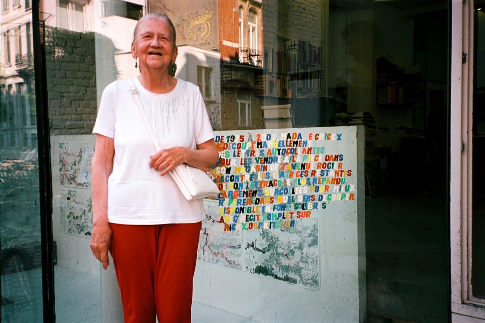 Woman standing in front of a window, inside of which is a display stand with an arrangement of tightly packed colourful letters.