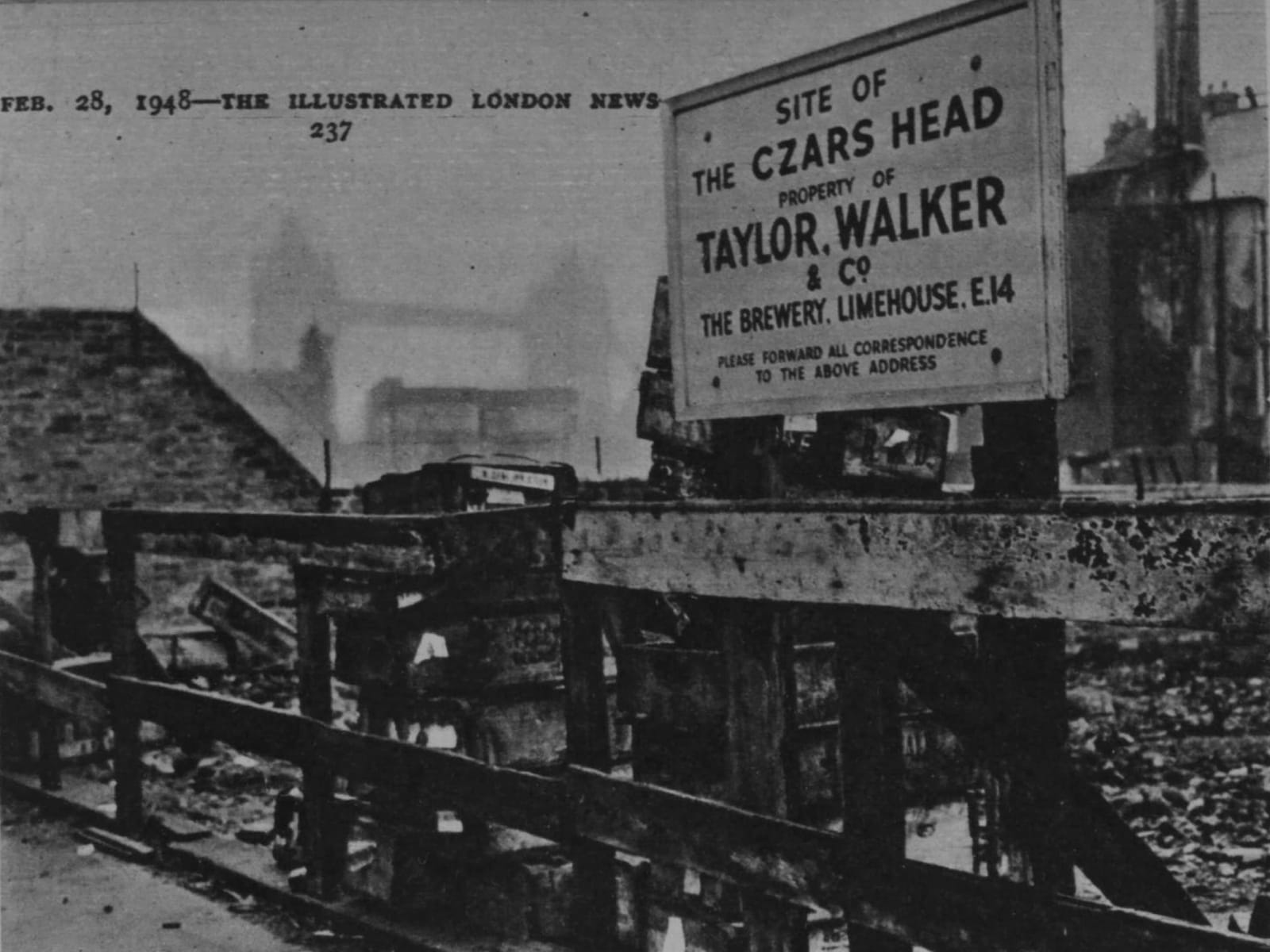 A wooden fence bars entry to rubble behind, with a sing protruding above it that reads, "Site of 'The Czars Head', property of Taylor, Walker & Co., The Brewery, Limehouse, E14. Please forward all correspondence to the above address."