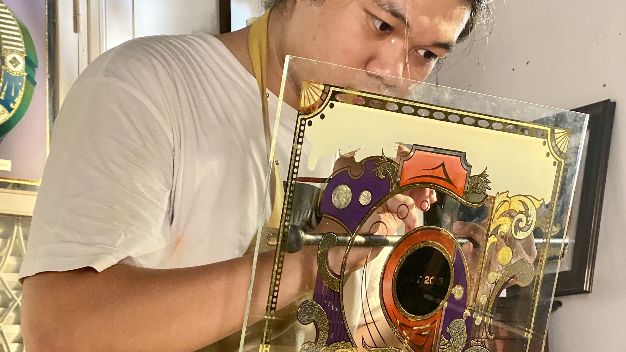 Sign painter working on a decorative glass panel.