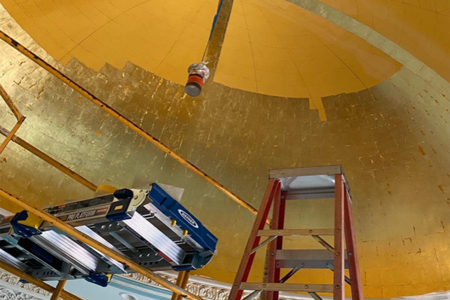 Ladders and a tower in place below a part-gilded dome.