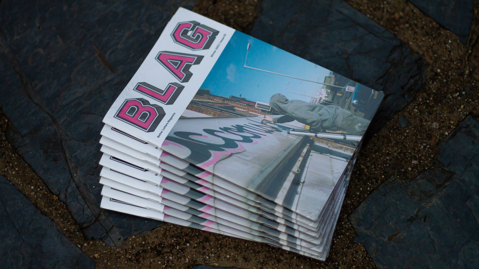 Pile of magazines on paving slabs.
