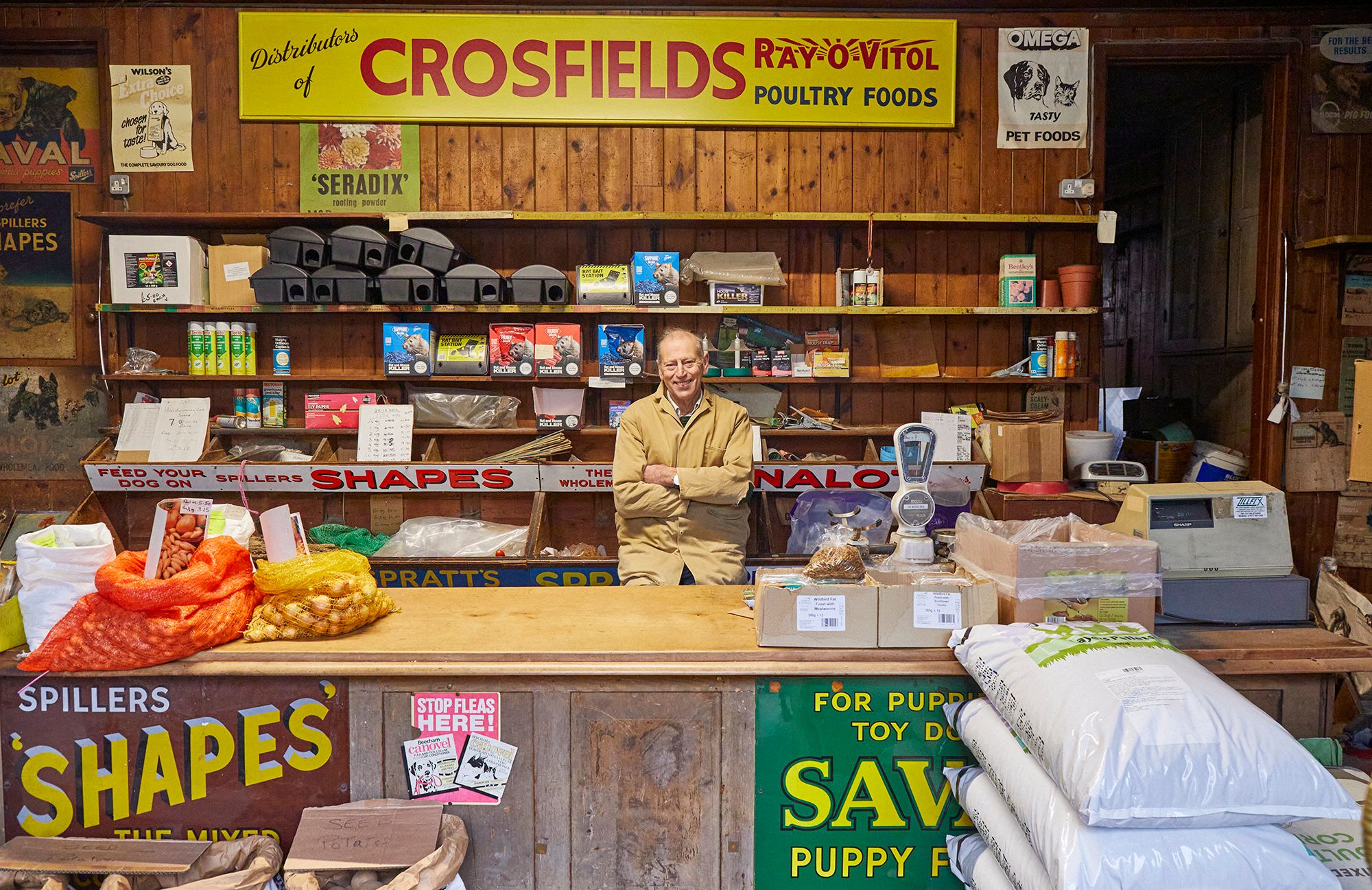 Man at a shop counter surrounded by signs.