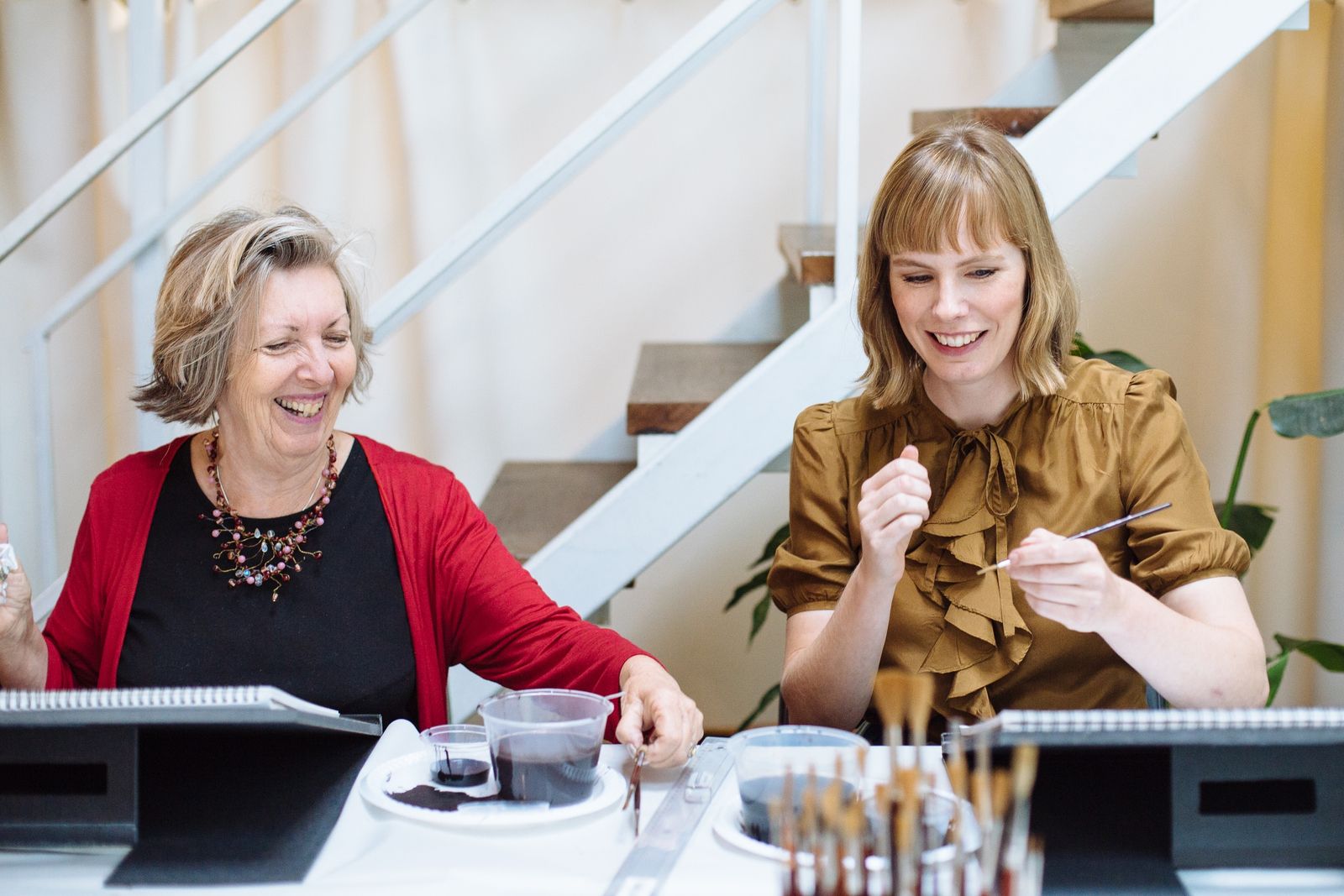 Two women at a table with easels in front of them.