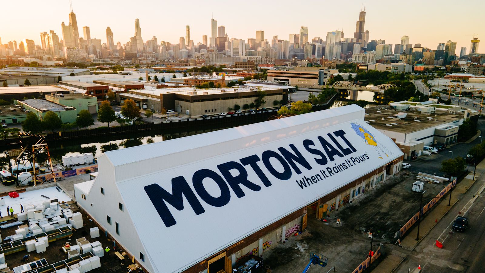 Drone photo of a large sign painted on a sloping roof with the city of Chicago in the background.