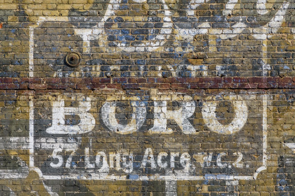 Layers of painted advertising fading on a portion of a brick wall.