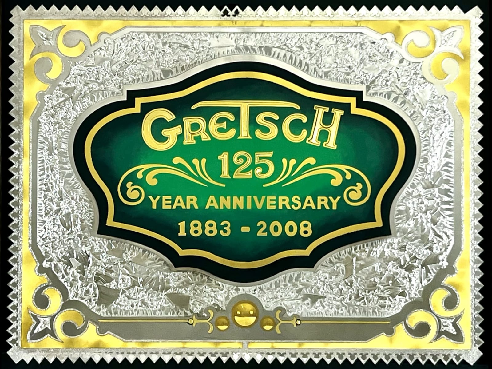 Decorative glass panel with gold, silver and green paint. It reads "Gretsch 125 year anniversary, 1883–2008".