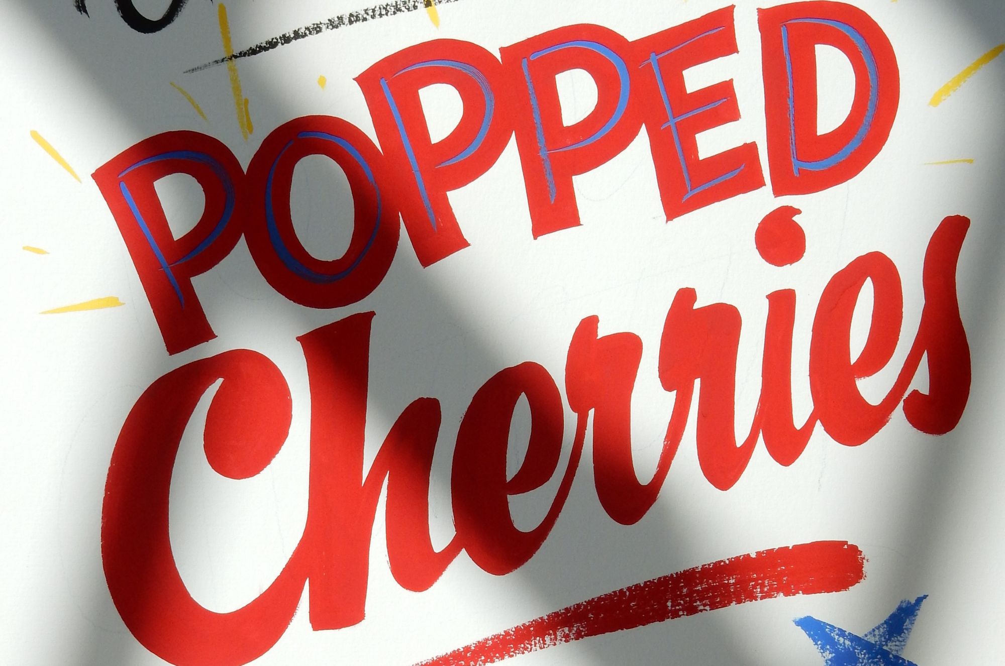 Hand-painted lettering that reads 'popped cherries'.