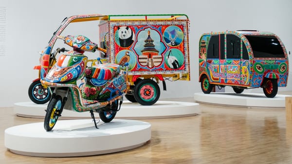 Exhibition space with brightly decorated vehicles on low plinths.